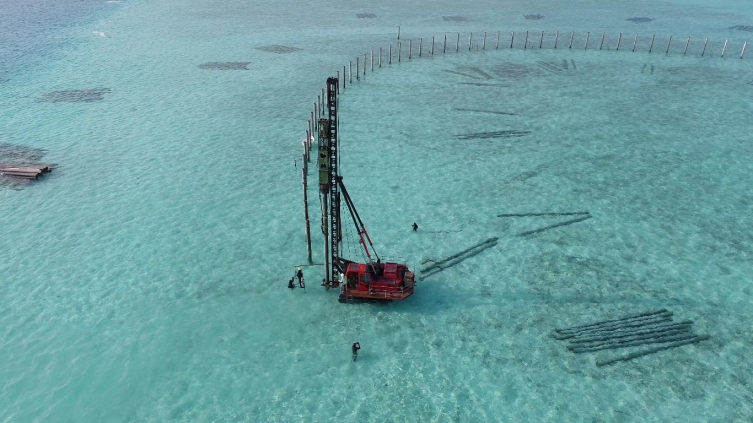 Piling rig on a barge installing piles in a Maldivian lagoon