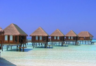 Thatched water villas on a lagoon, illustrative of the resort typology