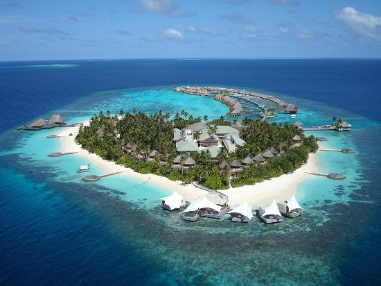 Aerial view of a resort island with overwater villas, illustrative